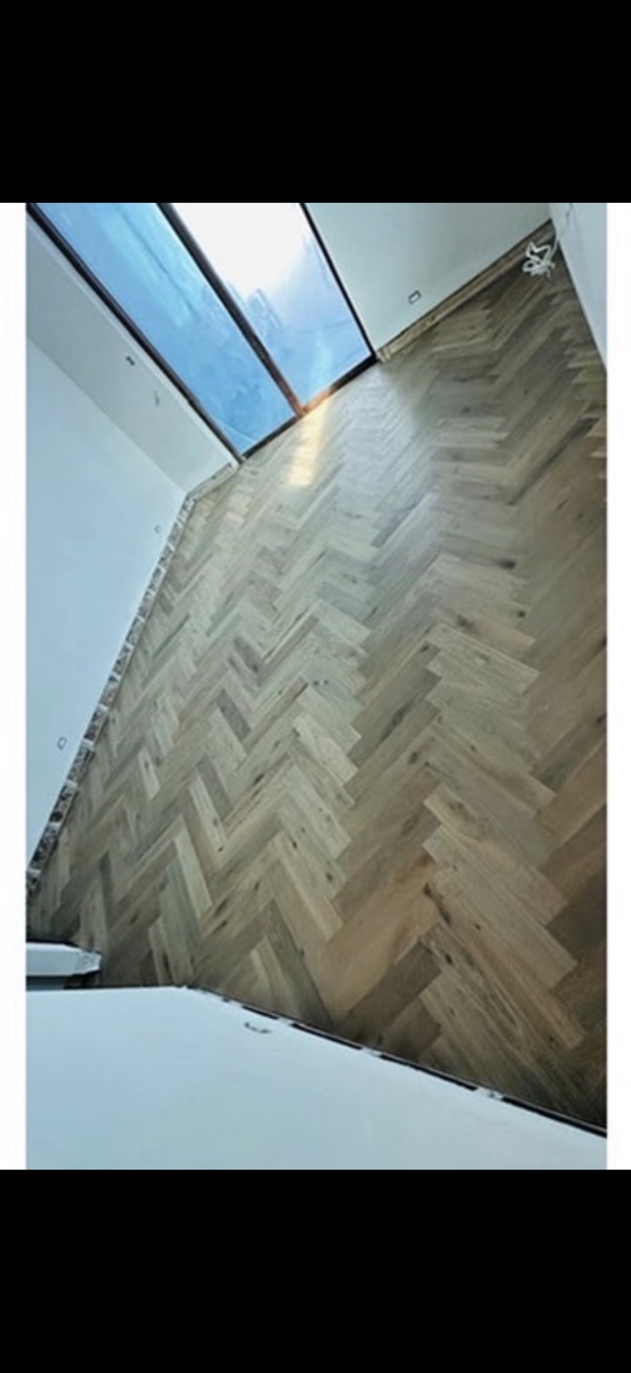 Light wood herringbone flooring beside sliding glass doors