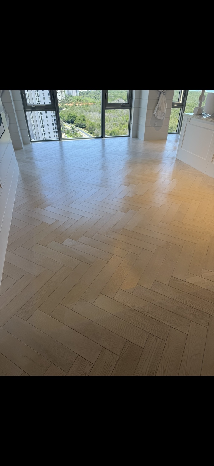 Light herringbone wood floor beside floor-to-ceiling windows