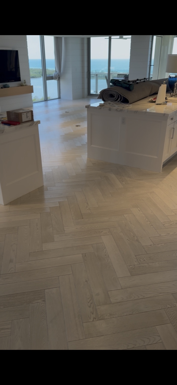 Light herringbone wood flooring around a kitchen island during an oil treatment project