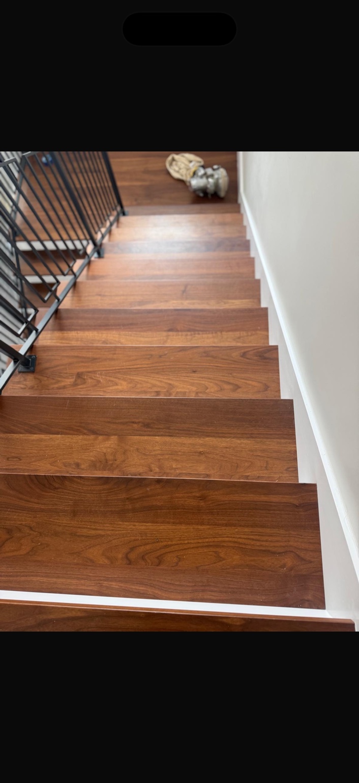 Rich wood grain on refinished stair treads with white risers and black railings